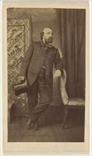 Full-bearded man holding a top hat, standing, leaning on chair back; Alexander Anderson, American, 1775 - 1870, 1860s; Albumen