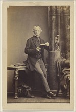 man seated on table, holding an opened book; Camille Silvy, French, 1834 - 1910, 1860s; Albumen silver print