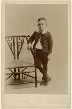 Young boy, standing, posed at angular chair; F.J. Klink, American, active 1890s, about 1890; Gelatin silver print
