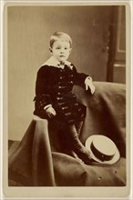 Little boy, seated on cloth, straw hat at feet; April 6, 1891; Albumen silver print
