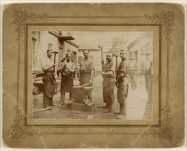 Five blacksmiths near an anvil, each holding a large hammer; about 1890; Gelatin silver print