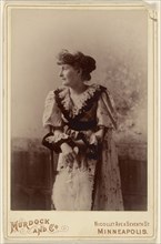 woman in profile, leaning on a chair, holding a feather fan; Murdock and Company; about 1890; Gelatin silver print
