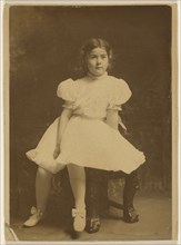 young girl in a white dress, seated; about 1920; Bromide print