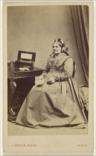 elderly woman seated near a table; J. Porter, American, 1901 - 1990, about 1865; Albumen silver print