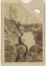 man sitting on rocks near a waterfall; about 1870; Albumen silver print