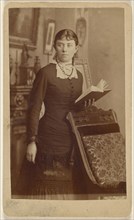 young woman holding an open book, standing; Spury, American, active Creston, Iowa 1860s - 1870s, 1865 - 1870; Albumen silver