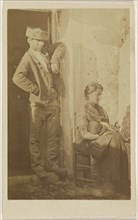 Man standing next to a seated woman holding a baby; 1865 - 1870; Albumen silver print
