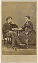 couple seated: man with hand to cheek, elbow on book; woman holding a parasol; S.G. Sheaffer & Company; 1865 - 1870; Albumen