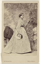 woman wearing a striped dress, holding a hat, standing; John Burton & Sons; 1864; Albumen silver print