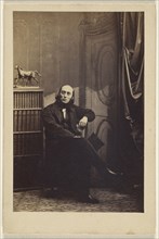 man seated with his legs crossed, holding a top hat; Camille Silvy, French, 1834 - 1910, about 1866; Albumen silver print