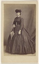 woman wearing a dark hat, holding a parasol, standing; Bailly & Maurice; 1865 - 1870; Albumen silver print