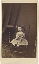 little girl holding a toy wooden horse, seated; 1865 - 1870; Albumen silver print
