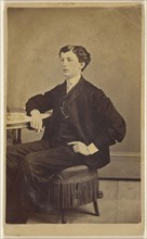 young man seated at a table; James S. Woodley, American, active 1860s, 1870 - 1875; Albumen silver print