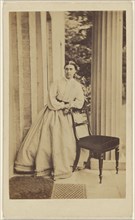 woman standing, leaning on chair back; J.G. & E.G. Short, British, 1865 - 1875; Albumen silver print