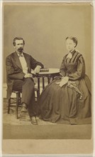 couple, both seated at a table with a book on top; the man has a bushy moustache; S.G. Sheaffer & Company; 1870 - 1875; Albumen
