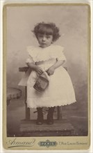 little girl standing in a chair, holding a pail with a ship on it; Armand; 1885 - 1895; Gelatin silver print