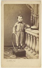 little boy standing on an ottoman, holding a hoop; A. Dupré, French, active 1860s, 1865 - 1875; Albumen silver print