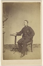 young man seated at a table with one hand on books; A. Crowe, British, active 1860s - 1870s, about 1865; Albumen silver print