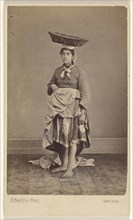 woman of Bayonne, France, wearing her native costume, standing, with a basket on top of her head; Ferdinand Berillon French