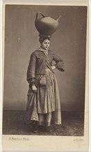 woman of Bayonne, France, wearing her native costume, standing, with a large ceramic pitcher on her head; Ferdinand Berillon