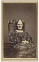 woman wearing a checkered dress, seated in a wicker chair; Abraham F. Burnham, American, active 1880s - 1890s, 1866; Albumen