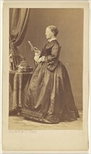 woman, standing, looking at a book; Disdéri & Cie; 1862-1865; Albumen silver print