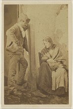 Man with round cap standing next to a seated woman with baby; 1865 - 1870; Albumen silver print