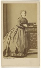 woman standing, leaning against a credenza; Bayard & Bertall; about 1861; Albumen silver print