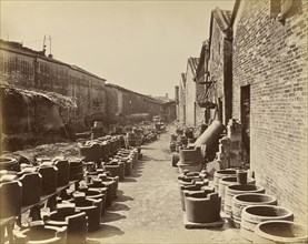 View of an alley bordered by brick buildings and containers on the ground; Unknown maker; China; about 1870; Albumen silver