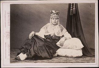Algerian woman seated on floor with arm resting on cushions, Cities and sites cabinet card collection, Veuve Plasse et Oberty