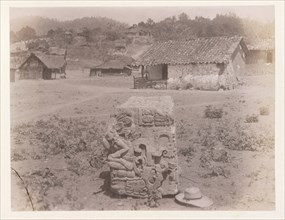 Carved block with hat in foreground and village behind, Edmund Lincoln miscellaneous papers relating to the excavation of Maya