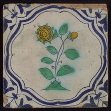 Tile, flower on plot in blue, green, and yellow on white, inside frame with accolades, corner motif, wing, wall tile