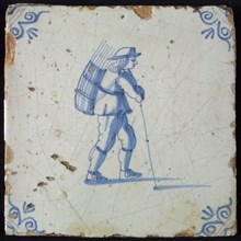 Occupation tile, blue with an image of man with hat and basket with stems on the back and stick in the hand, corner pattern ox