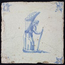 Occupation tile, blue with an image of woman with high basket of bread On the back, stick in the hand, corner motif of ox's head