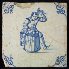 Occupation tile, blue with seated blacksmith with raised hammer and anvil, corner motif oxen head, wall tile tile sculpture