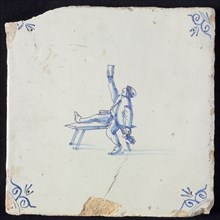 Figure tile, blue with man sitting with one leg on bench, lifting glass, another hand beer jug, corner pattern ox-head, wall