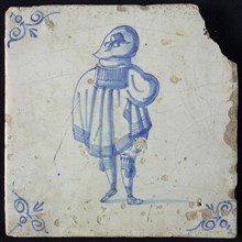 Wijtmans, Figure tile, blue with standing man seen from behind, big hat, and wide cape, corner patterned ox head, wall tile