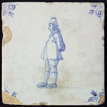 Figure tile, blue with standing man seen 'and profile', belly forward, arms on the back, corner pattern ox head, wall tile