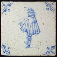 Figure tile, blue with standing man seen 'and profile', with wide cape and big hat, corner pattern ox head, wall tile