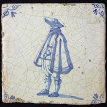 Figure tile, blue with standing man with wide cape and big hat, corner pattern ox's head, wall tile tile sculpture ceramic