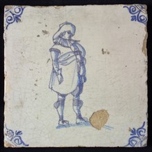 Figure tile, blue with standing man with big hat, stands with big belly forward, corner pattern ox-head, wall tile