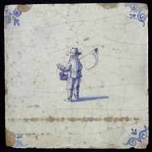 Figure tile, blue with farmer with scythe over the shoulder and basket in the hand, corner motif oxen head, wall tile