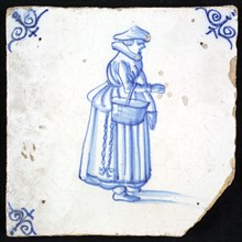 Figure tile, blue with lady with big hat, basket on the arm and chain with keys on the skirt, corner pattern ox-head, wall tile