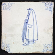 Figure tile, blue with civilian woman with hood, cloak that reaches from the head almost to the ground, corner motif oxen head