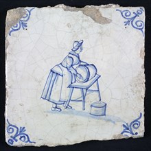 Figure tile, blue with woman cleaning barrel, on table, corner motif oxen head, wall tile tile sculpture ceramic earthenware