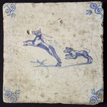 Animal tile, jumping dog hunting behind jumping deer to the left, in blue on white, corner motif oxen head, wall tile