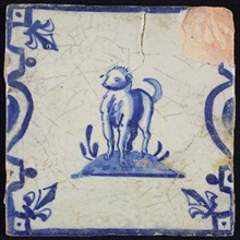 Animal tile, standing dog to the left on plot between balusters, in blue on white, corner pattern French lily, wall tile