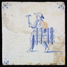Occupation tile, blue with glazier, man walking with frame and hammer, corner motif spider, wall tile tile sculpture ceramic