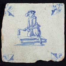 Figure tile, blue with woodworker kneeling on plank, with tassel, corner motif lily, wall tile tile sculpture ceramic