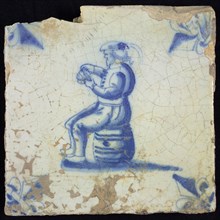 Figure tile, blue with man sitting on barrel with playing cards in hand, corner motif lily, wall tile tile sculpture ceramic